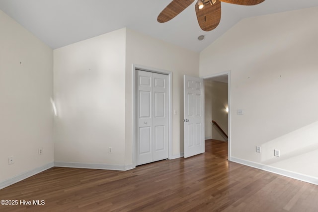 unfurnished bedroom featuring a closet, lofted ceiling, dark wood-style flooring, and baseboards