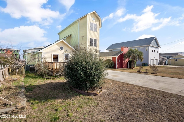 view of front of property featuring driveway, a front yard, central AC unit, and a wooden deck