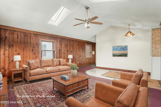 living area featuring a textured ceiling, wood walls, and lofted ceiling with skylight