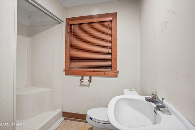 bathroom featuring baseboards, a sink, and toilet