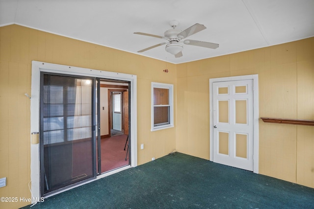 empty room featuring a ceiling fan, dark colored carpet, and vaulted ceiling