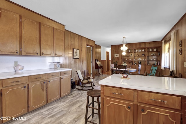 kitchen featuring a breakfast bar area, pendant lighting, and wood walls