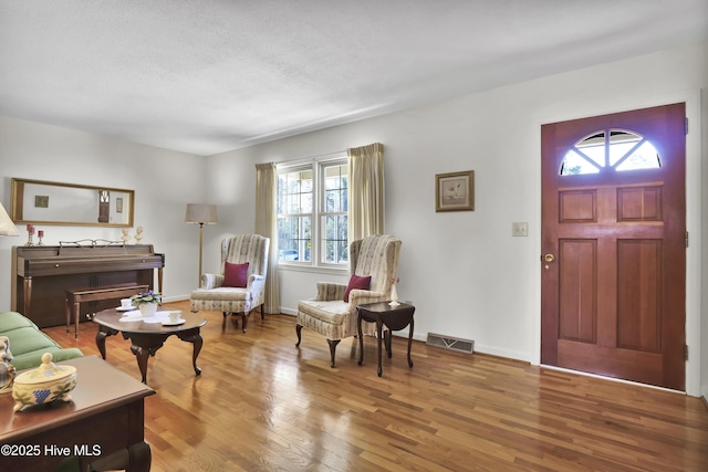 foyer entrance with hardwood / wood-style floors and a textured ceiling