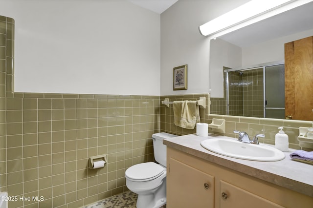 bathroom featuring vanity, toilet, tile walls, and walk in shower