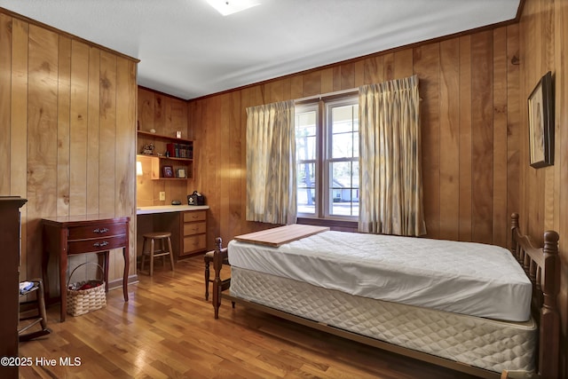 bedroom featuring wood-type flooring, built in desk, and wooden walls