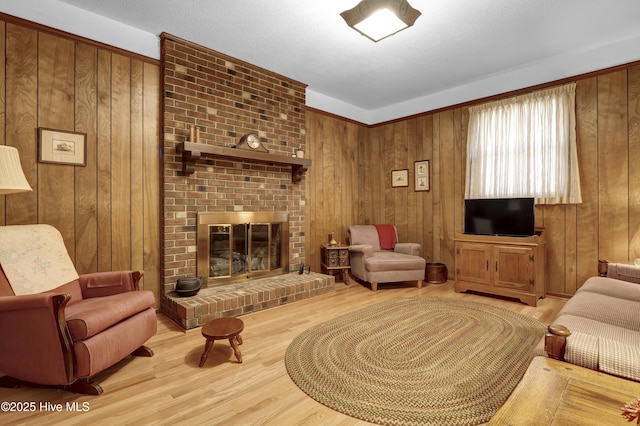 living room featuring light wood-type flooring, a fireplace, and wooden walls