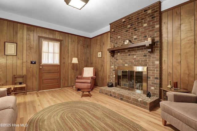 living room with hardwood / wood-style flooring, a brick fireplace, and wooden walls