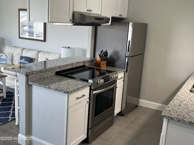 1801 Canal Dr Unit D14, Carolina Beach, NC 28428 - kitchen with stainless steel electric range, under cabinet range hood, white cabinets, light stone counters, and baseboards