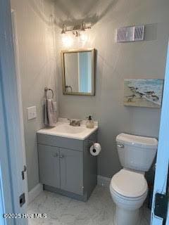 half bath featuring toilet, baseboards, and vanity