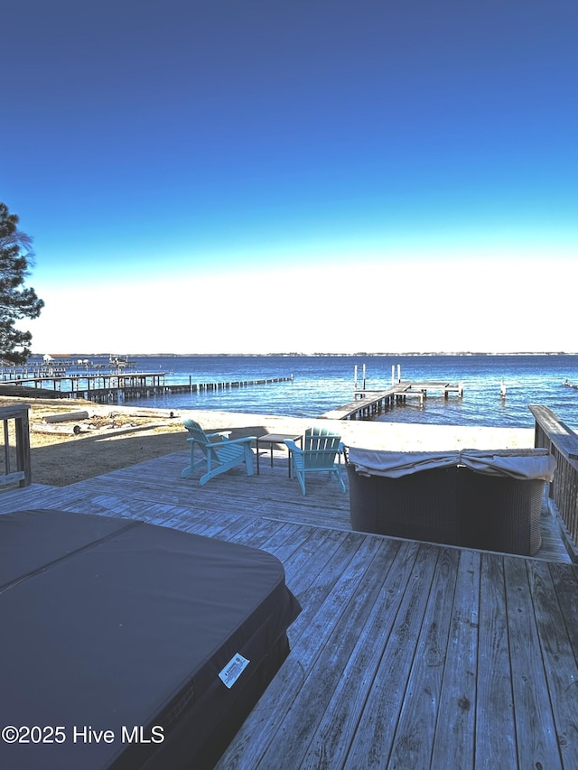 wooden terrace featuring a covered hot tub and a water view