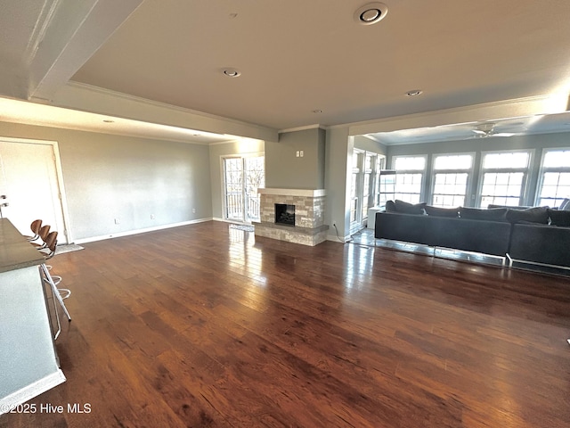 unfurnished living room featuring dark hardwood / wood-style floors, ornamental molding, and a fireplace