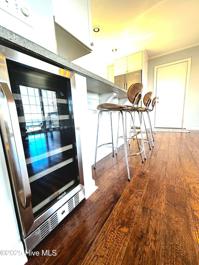 hallway featuring hardwood / wood-style flooring, ornamental molding, and beverage cooler