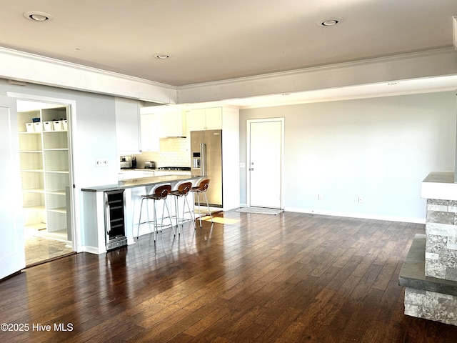 kitchen with dark hardwood / wood-style floors, a breakfast bar, white cabinetry, wine cooler, and high end fridge