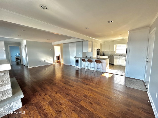 kitchen featuring a breakfast bar area, dark hardwood / wood-style floors, a kitchen island, and white cabinets