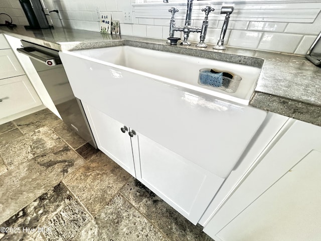 interior space with backsplash, sink, and white cabinets