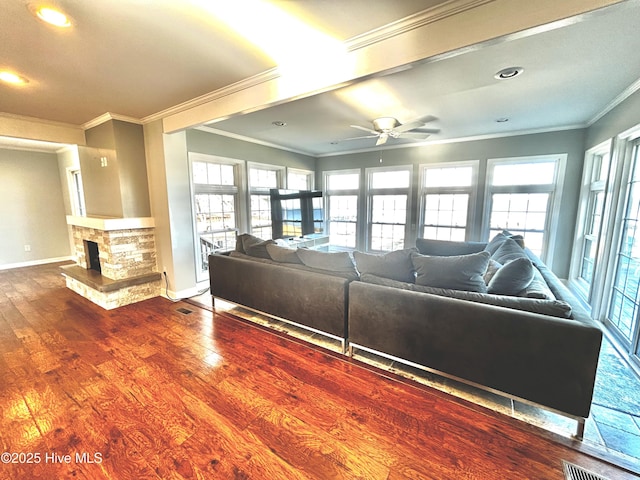 living room featuring ornamental molding, wood-type flooring, a fireplace, and a wealth of natural light