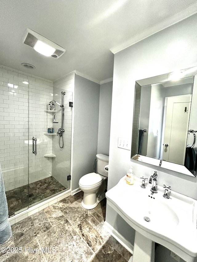 bathroom featuring crown molding, toilet, a shower with shower door, and sink