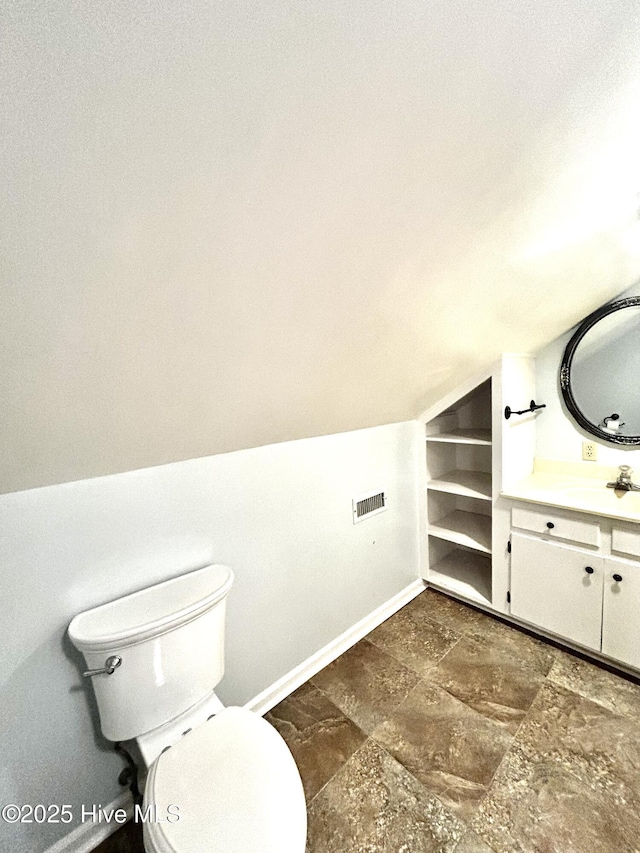 bathroom with vanity, toilet, and vaulted ceiling