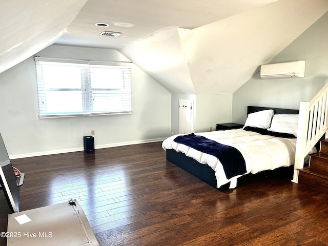 bedroom featuring dark hardwood / wood-style flooring, lofted ceiling, and a wall mounted AC