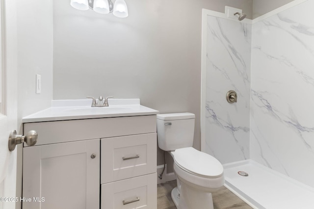 bathroom with tiled shower, vanity, and toilet