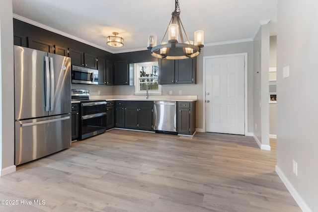 kitchen featuring ornamental molding, appliances with stainless steel finishes, hanging light fixtures, and light wood-type flooring