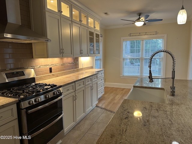 kitchen with ornamental molding, a sink, double oven range, wall chimney exhaust hood, and decorative backsplash