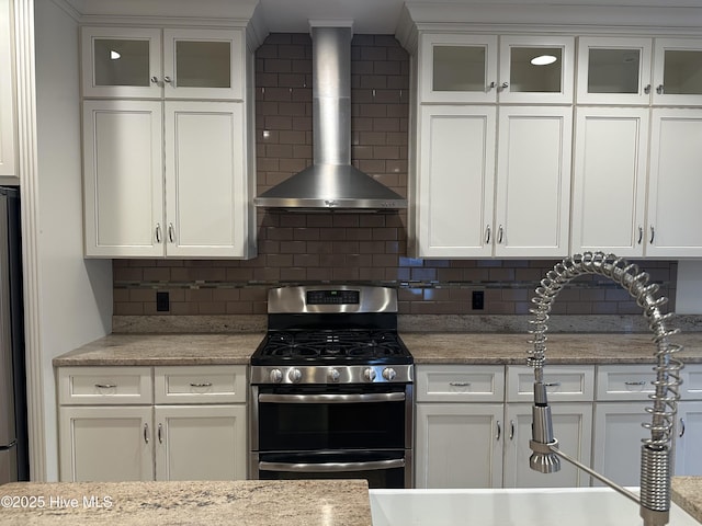 kitchen featuring appliances with stainless steel finishes, white cabinets, and wall chimney range hood