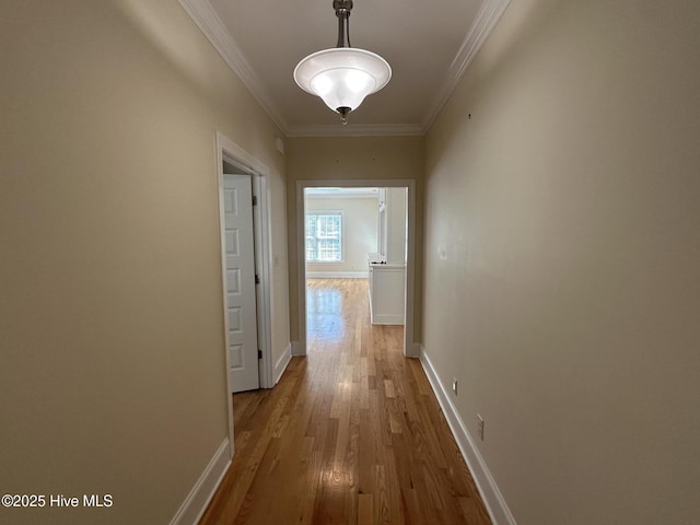 hallway featuring crown molding, baseboards, and wood finished floors