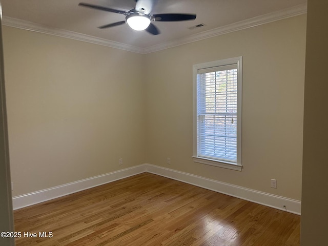 empty room featuring baseboards, wood finished floors, visible vents, and ornamental molding