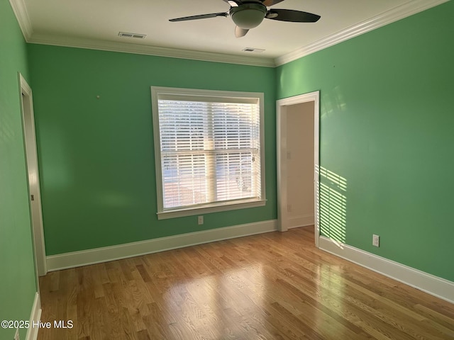 unfurnished room with visible vents, baseboards, wood finished floors, and crown molding