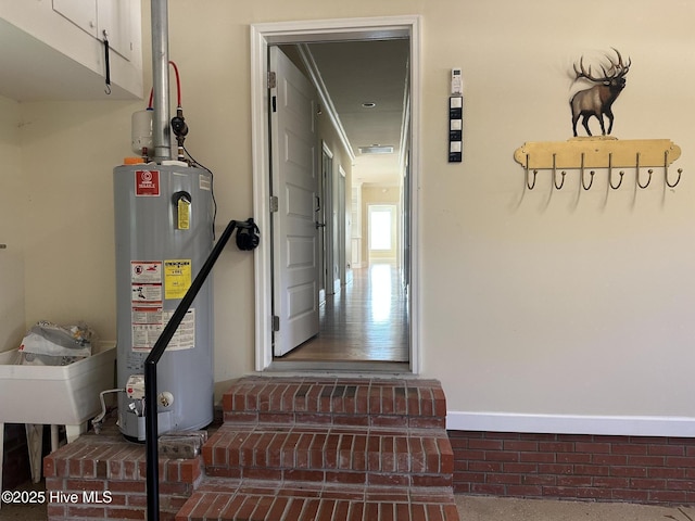 corridor with gas water heater and baseboards