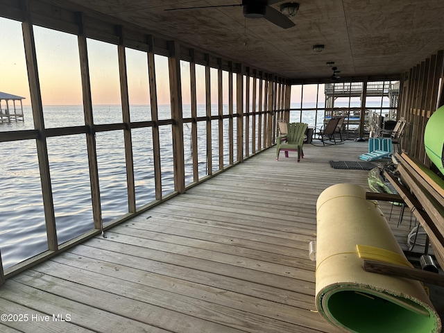 sunroom / solarium featuring ceiling fan and a water view