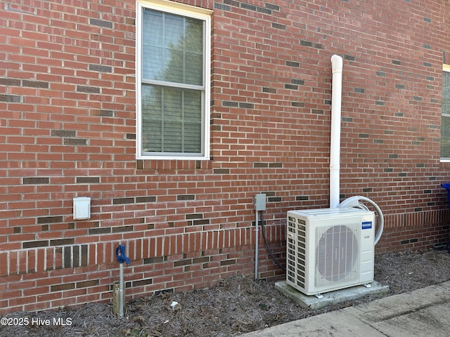 exterior details featuring ac unit and brick siding