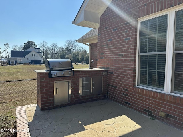 view of patio featuring area for grilling, a sink, exterior kitchen, and fence