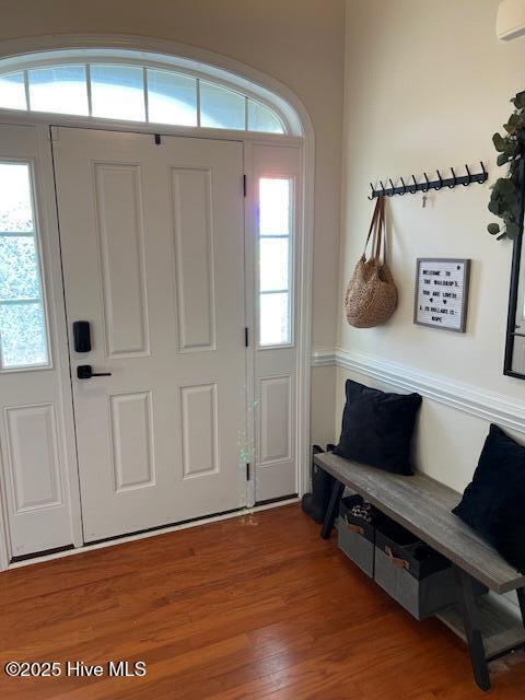 foyer with hardwood / wood-style flooring, an AC wall unit, and a healthy amount of sunlight