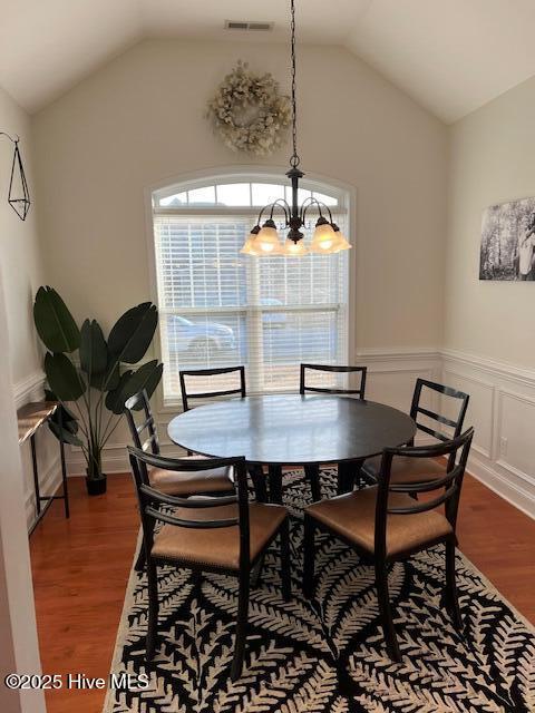 dining space with lofted ceiling, hardwood / wood-style flooring, and a chandelier