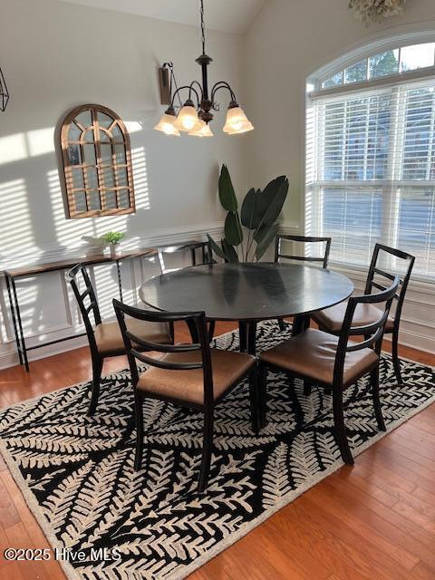 dining area featuring an inviting chandelier, hardwood / wood-style flooring, and lofted ceiling