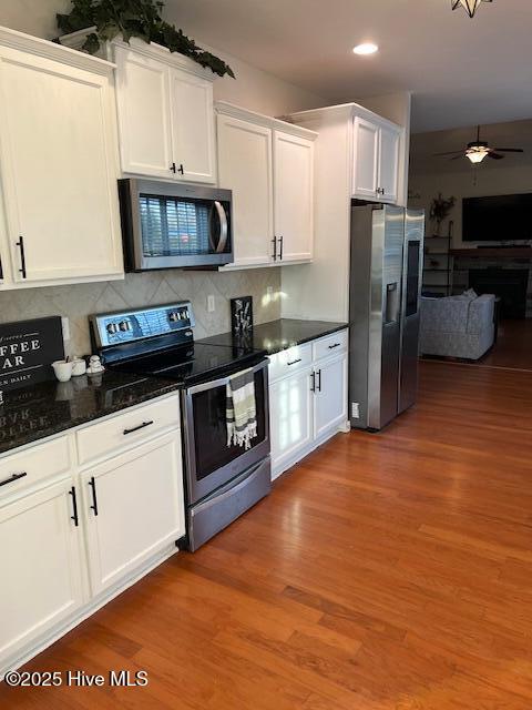 kitchen featuring appliances with stainless steel finishes, white cabinetry, dark hardwood / wood-style flooring, decorative backsplash, and ceiling fan