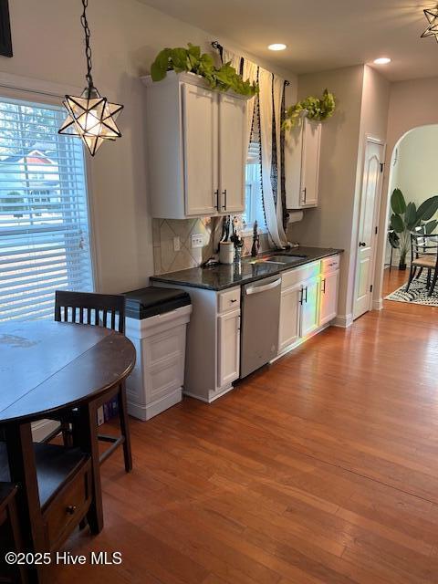 kitchen featuring white cabinetry, stainless steel dishwasher, hardwood / wood-style floors, and pendant lighting