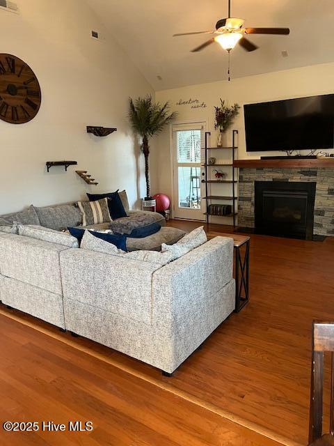 living room featuring a fireplace, vaulted ceiling, wood-type flooring, and ceiling fan