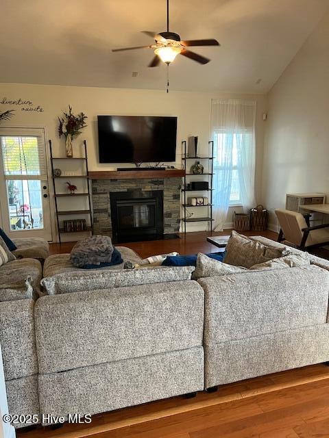 living room featuring hardwood / wood-style flooring, ceiling fan, plenty of natural light, and a stone fireplace