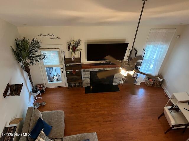 living room featuring wood-type flooring and a stone fireplace