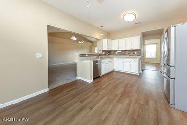 kitchen with sink, dishwasher, white cabinets, decorative light fixtures, and kitchen peninsula