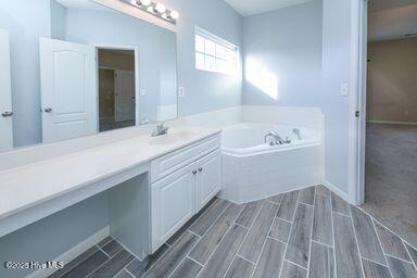 bathroom featuring vanity and tiled bath