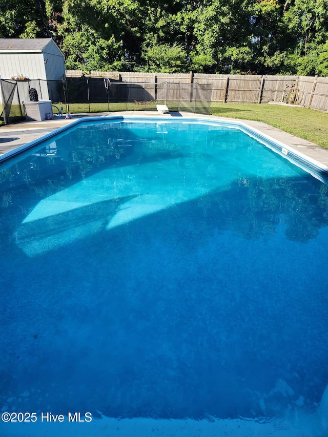 view of swimming pool with a diving board, a shed, and a lawn