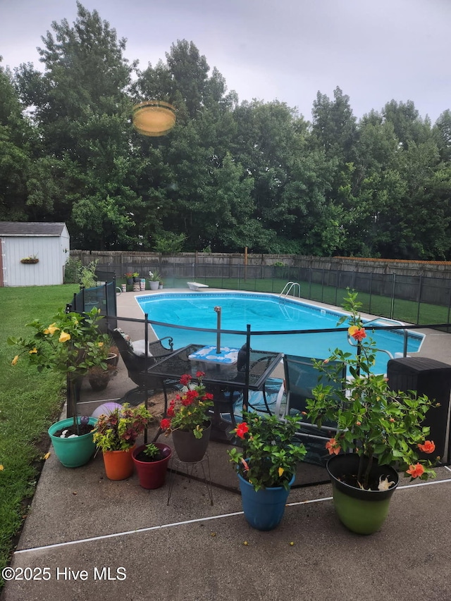 view of pool with a storage shed, a yard, and a diving board