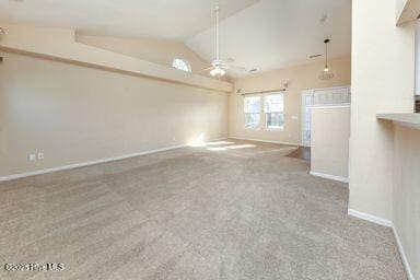 unfurnished living room featuring ceiling fan, vaulted ceiling, and light carpet