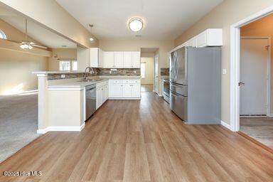 kitchen with sink, hardwood / wood-style flooring, appliances with stainless steel finishes, white cabinetry, and decorative backsplash