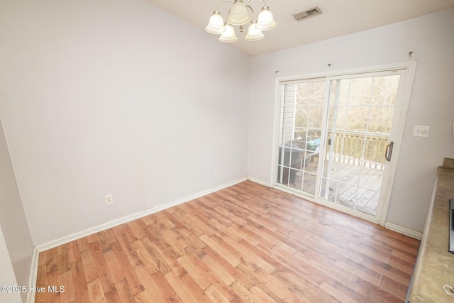 empty room with light hardwood / wood-style flooring and a notable chandelier