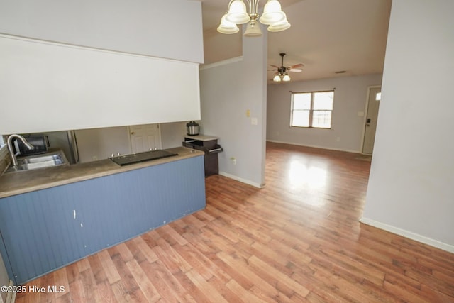 kitchen with ceiling fan with notable chandelier, blue cabinets, sink, and wood-type flooring